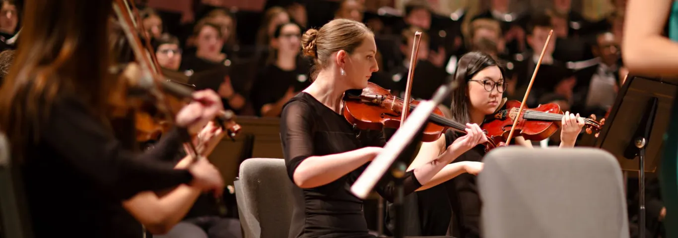 violinists seated in front of a choir